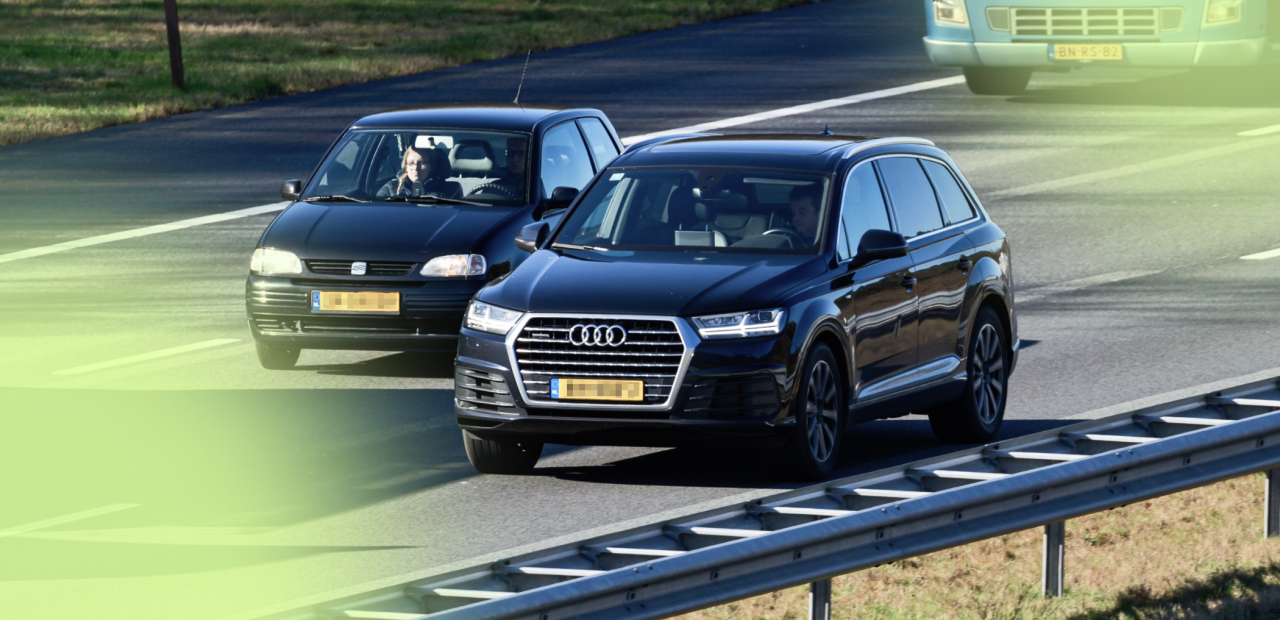 Twee auto's naast elkaar op de snelweg, een enorme audi en een kleine fiat