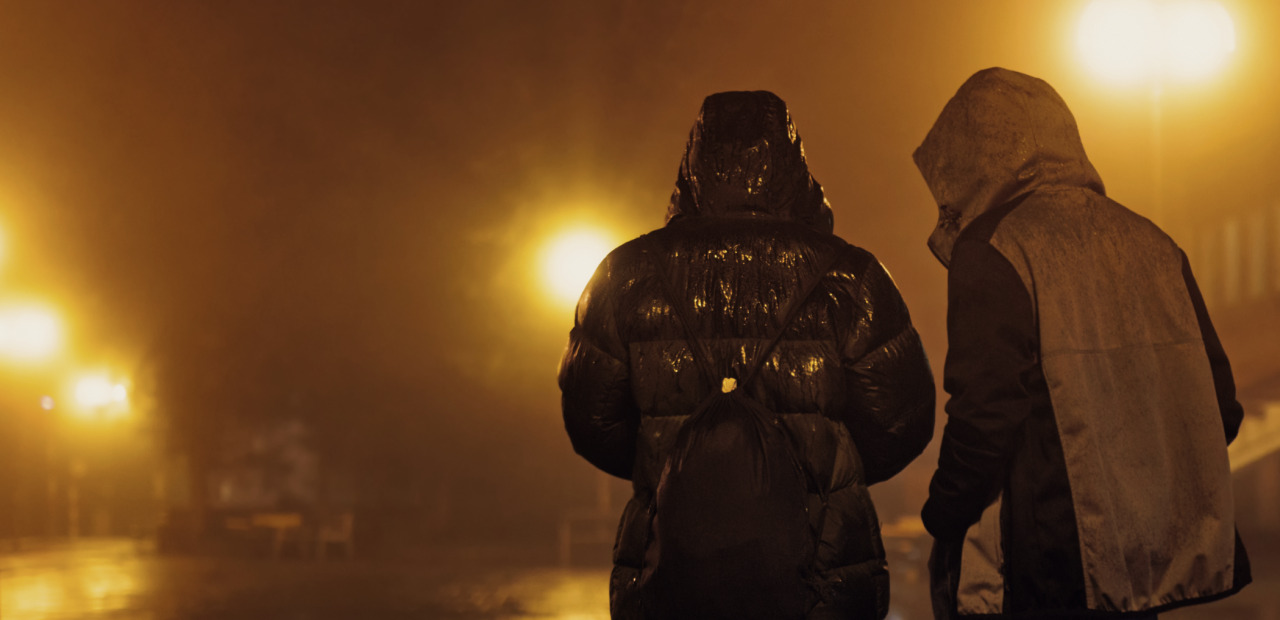 Twee jongeren die 's avonds op straat lopen