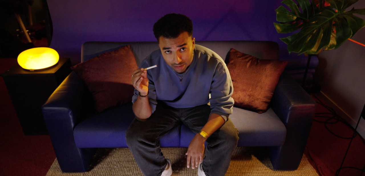 Benji zit in de studio en heeft een niet-aangestoken sigaret in zijn hand.