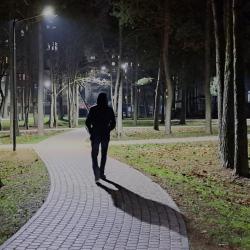 Een man met een capuchon op loopt alleen door het park