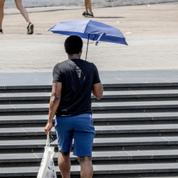 Een man loopt met een paraplu als bescherming tegen de zon