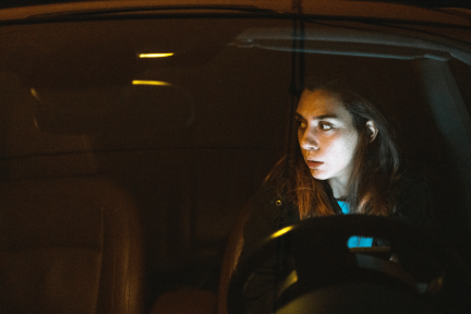 Vrouw die alert om zich heen kijkt terwijl zij in de auto zit.
