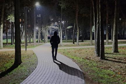 Een man met een capuchon op loopt alleen door het park