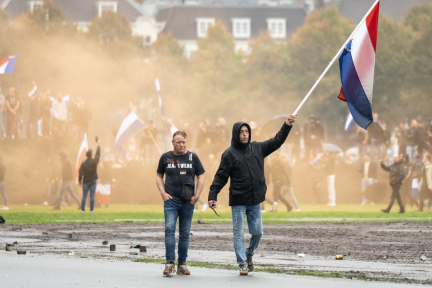 Mannen zwaaien met de Nederlandse vlag tijdens rellen op het Malieveld. 