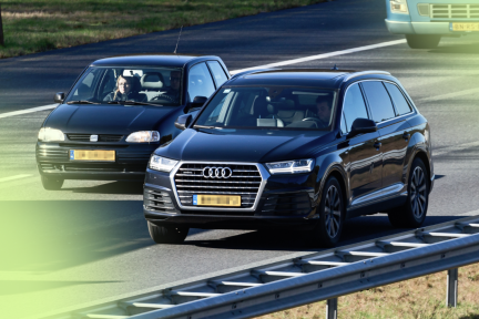 Twee auto's naast elkaar op de snelweg, een enorme audi en een kleine fiat