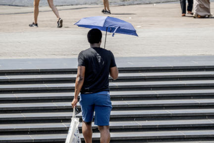 Een man loopt met een paraplu als bescherming tegen de zon