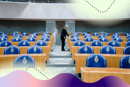 We zien een lege Tweede Kamer en verderop staat een Kamerlid