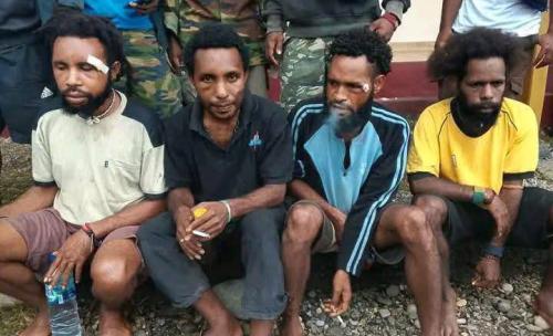 Groepsfoto van vier gemartelde activisten zitten op een stoepje voor het politiekantoor in Dekai, Yahukimo, West-Papoea