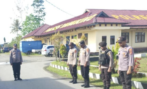 Foto van zijkant van politiekantoor in Yahukimo, met ervoor enkele politieagenten