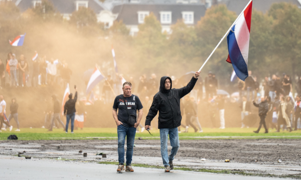Mannen zwaaien met de Nederlandse vlag tijdens rellen op het Malieveld. 