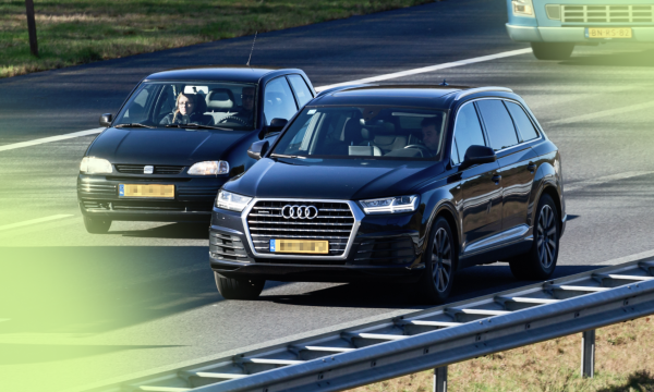 Twee auto's naast elkaar op de snelweg, een enorme audi en een kleine fiat