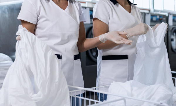 Afbeelding met daarop twee medewerkers in een wasserij, foto ter illustratie