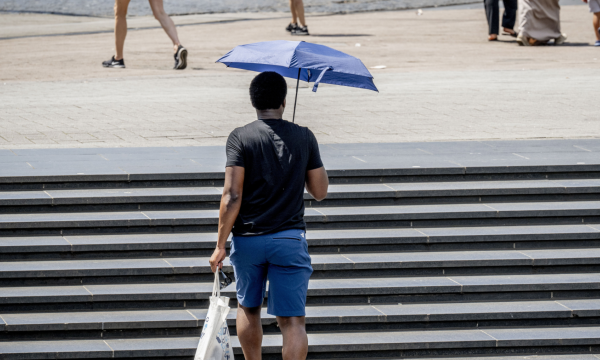 Een man loopt met een paraplu als bescherming tegen de zon