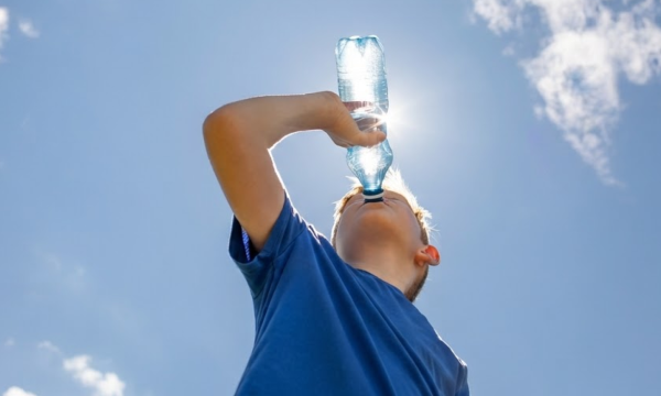 Kind drinkt water uit een flesje op een zonnige dag
